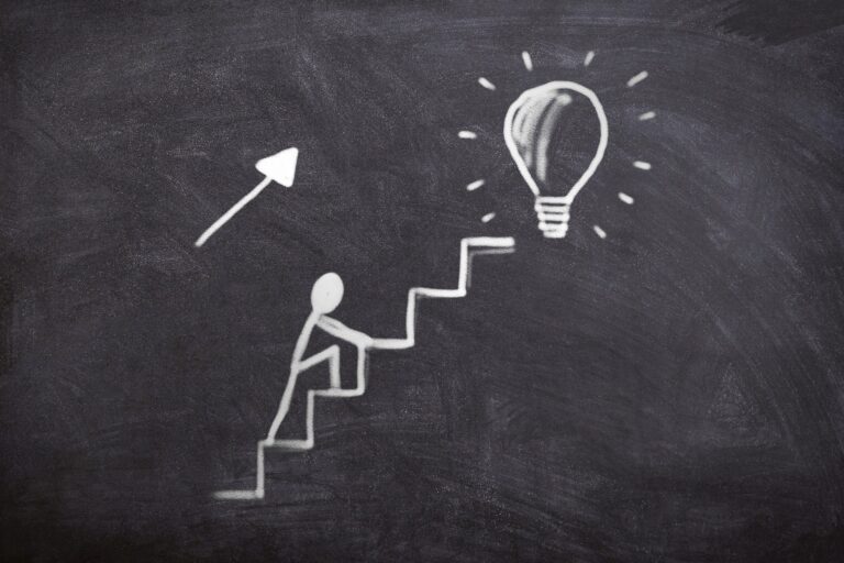 Chalkboard with an image of a person climbing steps towards a lightbulb